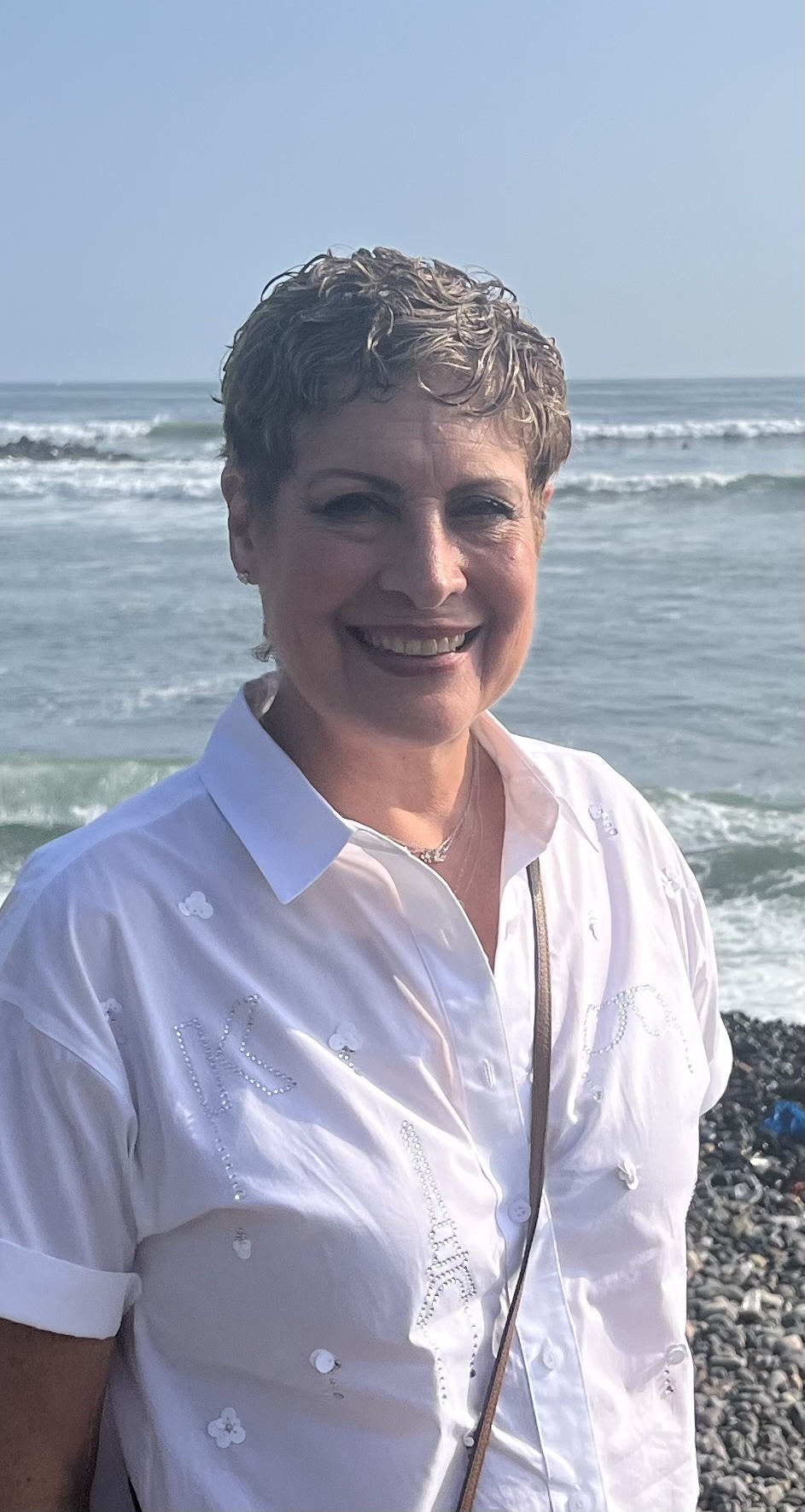 Director Lil Winestone Woman with short blonde hair smiling at the camera, wearing a light-colored top.
