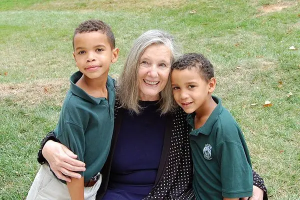 Ellen-Cromwell-Mother-Of-Georgetwon-Hill-Early-School Ellen Cromwell kneeling beside two students.