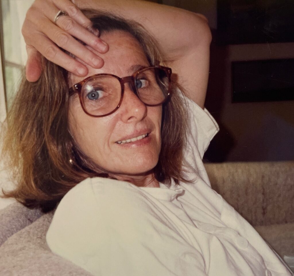 Woman with glasses sitting on a sofa.