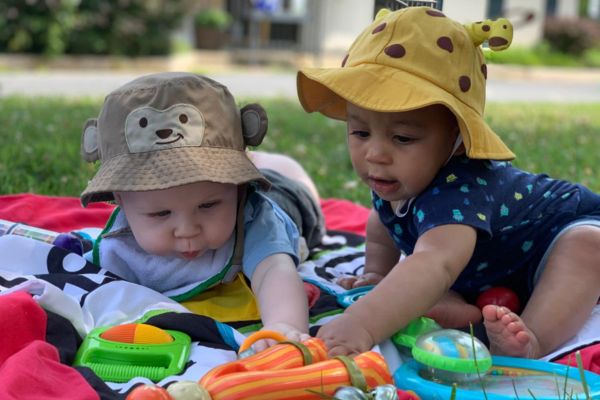 Infant_Plan_4 two infants playing with toys on a blanket in the park